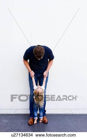 Portrait of mature man with daughter leaning back in front of white wall View Large Photo Image Picture - Portrait of mature man with daughter leaning back in front of white wall. Fotosearch