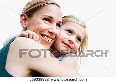 Portrait of mid adult woman and daughter hugging in front of white wall View Large Photo Image Stock Image - Portrait of mid adult woman and daughter hugging in front of white wall. Fotosearch