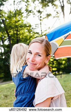 Portrait of mid adult woman and toddler daughter hugging in park View Large Photo Image Stock Image - Portrait of mid adult woman and toddler daughter hugging in park. Fotosearch