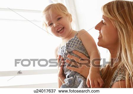 Portrait of mid adult woman and toddler daughter at window View Large Photo Image Stock Photo - Portrait of mid adult woman and toddler daughter at window. Fotosearch