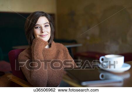 Stock Image - Portrait of mid adult woman sitting at cafe table. Fotosearch