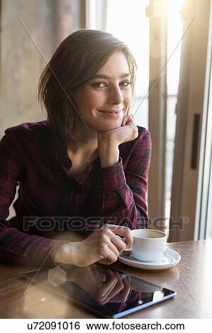 Portrait of mid adult woman with coffee and digital tablet at cafe table View Large Photo Image Stock Photograph - Portrait of mid adult woman with coffee and digital tablet at cafe table. Fotosearch