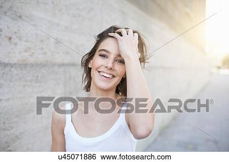 Portrait of mid adult woman with hand in hair on sunlit city sidewalk View Large Photo Image Stock Photograph - Portrait of mid adult woman with hand in hair on sunlit city sidewalk. Fotosearch