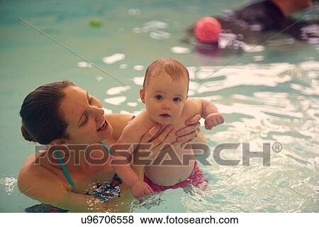 Stock Photo - Portrait of mother holding baby girl in swimming pool. Fotosearch