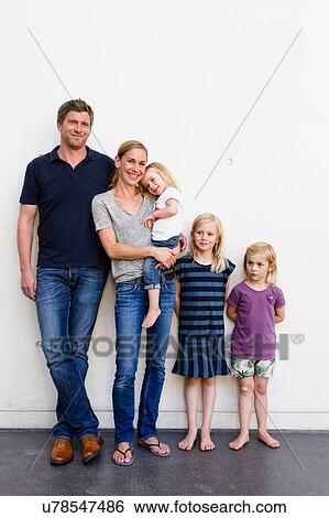 Portrait of parents and three young daughters standing in front of white wall View Large Photo Image Stock Photograph - Portrait of parents and three young daughters standing in front of white wall. Fotosearch