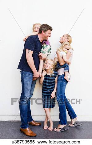 Portrait of parents and three young daughters in front of white wall View Large Photo Image Stock Photography - Portrait of parents and three young daughters in front of white wall. Fotosearch