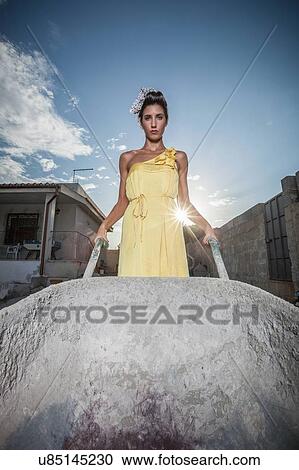 Portrait of sullen stylish young woman pushing wheelbarrow in garden View Large Photo Image Stock Image - Portrait of sullen stylish young woman pushing wheelbarrow in garden. Fotosearch