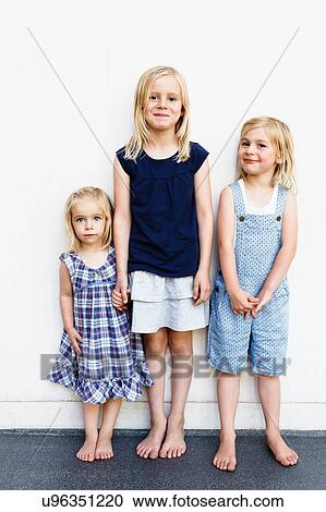 Portrait of three young sisters standing in front of white wall View Large Photo Image Stock Image - Portrait of three young sisters standing in front of white wall. Fotosearch