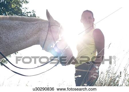 Portrait of woman with grey horse against sunlit sky View Large Photo Image Stock Photograph - Portrait of woman with grey horse against sunlit sky. Fotosearch