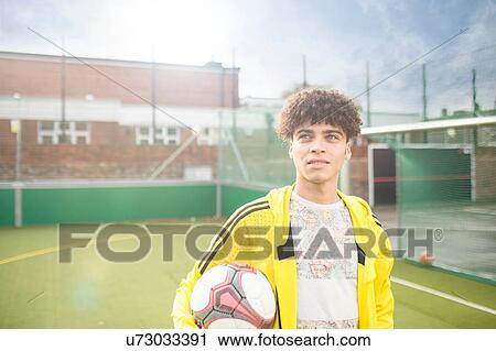 Portrait of young man holding football, on urban football pitch View Large Photo Image Stock Image - Portrait of young man holding football, on urban football pitch. Fotosearch
