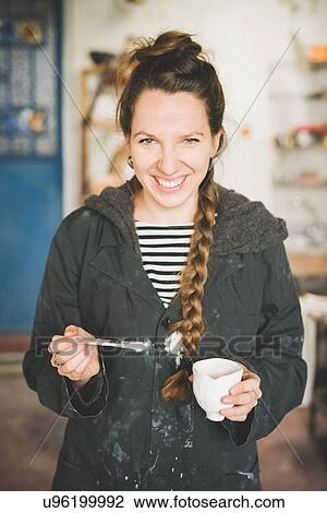 Portrait of young woman holding clay pot and paintbrush looking at camera smiling View Large Photo Image Stock Image - Portrait of young woman holding clay pot and paintbrush looking at camera smiling. Fotosearch
