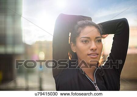 Portrait of young woman stretching, arms behind head View Large Photo Image Stock Image - Portrait of young woman stretching, arms behind head. Fotosearch