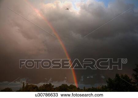 Stock Image - Rainbow in cloudy sky. Fotosearch