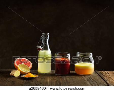 Picture - Raw juices in glass bottle and jars, dark background. Fotosearch