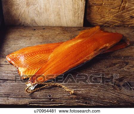 Stock Image - Raw smoked salmon with skin on rustic wooden table. Fotosearch