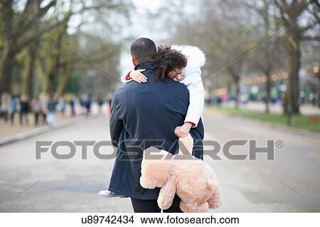 Rear view of father carrying sleeping daughter holding cuddly toy View Large Photo Image Picture - Rear view of father carrying sleeping daughter holding cuddly toy. Fotosearch