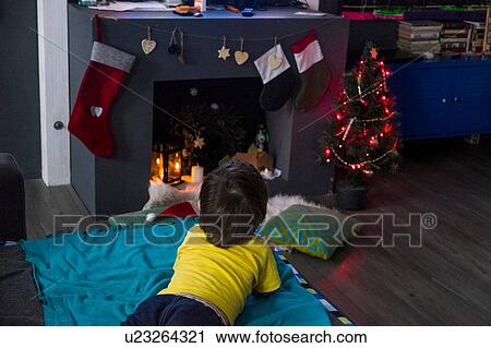 Rear view of male toddler lying on blanket gazing at christmas tree in front of fireplace View Large Photo Image Stock Image - Rear view of male toddler lying on blanket gazing at christmas tree in front of fireplace. Fotosearch