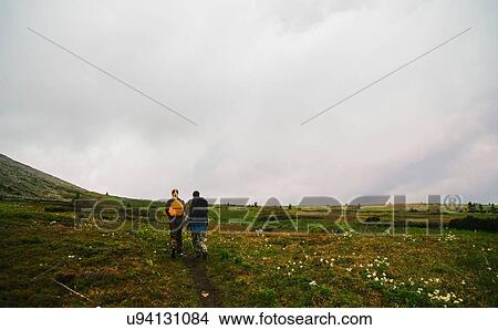 Picture - Rear view of man and woman hiking in valley landscape, Ural Mountains, Russia. Fotosearch