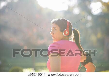 Rear view of mature woman wearing headphones and armband looking away View Large Photo Image Stock Image - Rear view of mature woman wearing headphones and armband looking away. Fotosearch