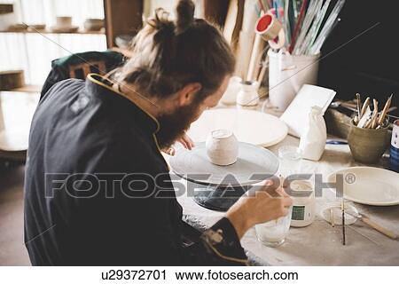 Rear view of mid adult man in workshop applying ceramic glaze to clay pot View Large Photo Image Stock Image - Rear view of mid adult man in workshop applying ceramic glaze to clay pot. Fotosearch