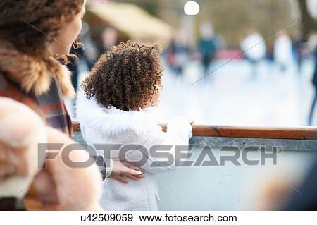 Rear view of mother and daughter watching people ice skating on ice rink View Large Photo Image Stock Photo - Rear view of mother and daughter watching people ice skating on ice rink. Fotosearch