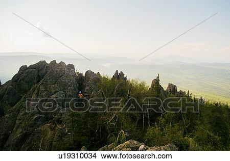 Rear view of teenage male hiker climbing rugged rock formation, Russia View Large Photo Image Picture - Rear view of teenage male hiker climbing rugged rock formation, Russia. Fotosearch