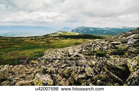 Rear view of woman hiking alone in rugged landscape, Ural Mountains, Russia View Large Photo Image Stock Photo - Rear view of woman hiking alone in rugged landscape, Ural Mountains, Russia. Fotosearch