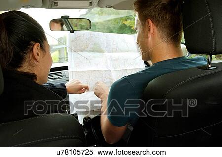 Stock Photography - Rear view of young couple reading map in car. Fotosearch
