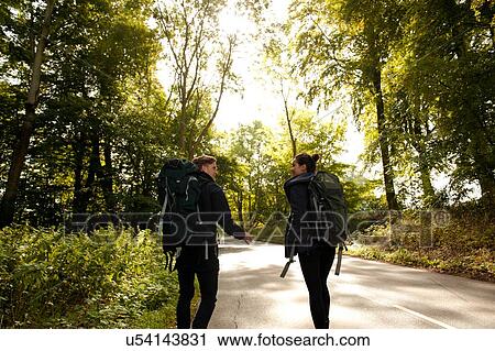 Rear view of young hiking couple chatting on rural road View Large Photo Image Stock Image - Rear view of young hiking couple chatting on rural road. Fotosearch
