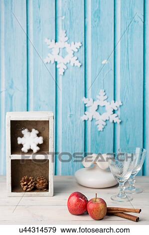 Red apples, cinnamon sticks, wine glasses, pine cone, paper snowflakes on blue wall View Large Photo Image Stock Photo - Red apples, cinnamon sticks, wine glasses, pine cone, paper snowflakes on blue wall. Fotosearch