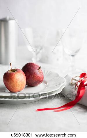 Stock Image - Red apples on plate, napkin tied with red ribbon. Fotosearch