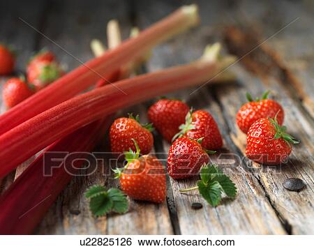 Stock Photograph - Rhubarb and strawberries on wood surface. Fotosearch