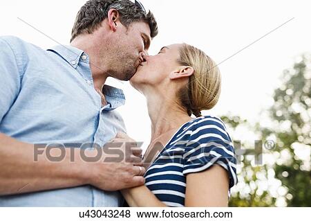 Stock Photo - Romantic couple kissing in park. Fotosearch