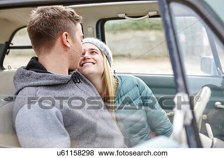 Stock Photo - Romantic young couple in front seat of car at beach. Fotosearch