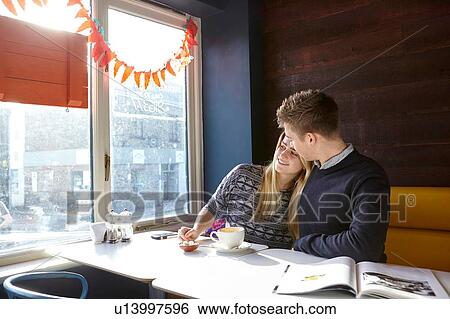 Stock Photograph - Romantic young couple on date in cafe window seat. Fotosearch
