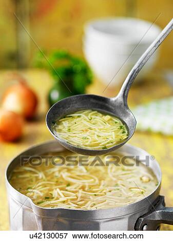 Stock Photo - Saucepan and ladle of chicken noodle soup with onions, herbs and stock. Fotosearch