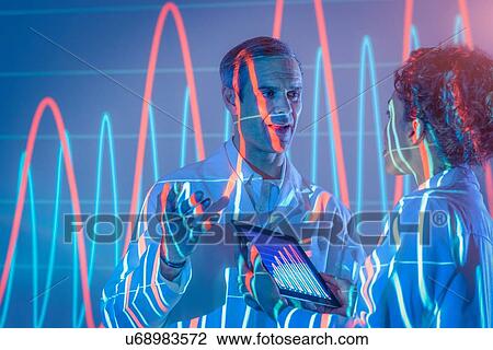 Stock Image - Scientists in discussion with graphical data projection. Fotosearch