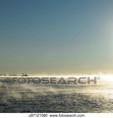Seascape with fishing boat on horizon in dawn sunlit mist View Large Photo Image Stock Image - Seascape with fishing boat on horizon in dawn sunlit mist. Fotosearch