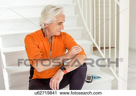 Stock Image - Senior man sitting on staircase preparing for run. Fotosearch