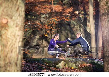 Side view of couple on rocks in forest face to face, holding hands, squatting balancing on one leg View Large Photo Image Stock Image - Side view of couple on rocks in forest face to face, holding hands, squatting balancing on one leg. Fotosearch