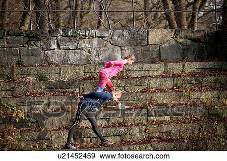 Side view of couple on stone steps bending over, hands behind back stretching View Large Photo Image Stock Photo - Side view of couple on stone steps bending over, hands behind back stretching. Fotosearch