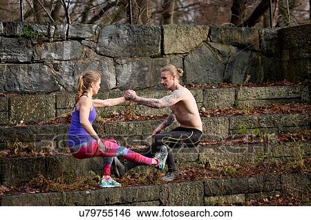 Side view of couple squatting on stone steps, face to face holding hands balancing on one leg View Large Photo Image Stock Photograph - Side view of couple squatting on stone steps, face to face holding hands balancing on one leg. Fotosearch