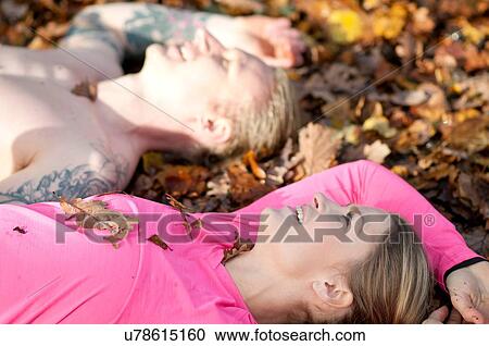 Side view of couples head and shoulders lying on autumn leaves looking up smiling View Large Photo Image Stock Image - Side view of couples head and shoulders lying on autumn leaves looking up smiling. Fotosearch