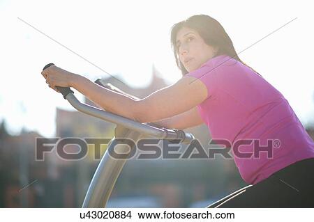 Side view of mature woman on outdoor exercise equipment looking away View Large Photo Image Picture - Side view of mature woman on outdoor exercise equipment looking away. Fotosearch