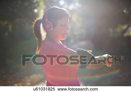 Side view of mature woman wearing headphones preparing armband View Large Photo Image Stock Photography - Side view of mature woman wearing headphones preparing armband. Fotosearch