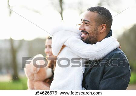 Stock Photograph - Side view of smiling father carrying daughter. Fotosearch