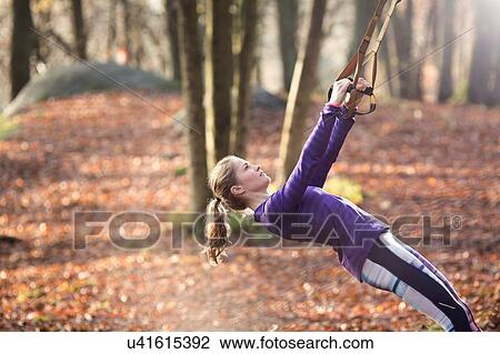Side view of young woman in forest leaning back using resistance bands, looking up View Large Photo Image Stock Image - Side view of young woman in forest leaning back using resistance bands, looking up. Fotosearch