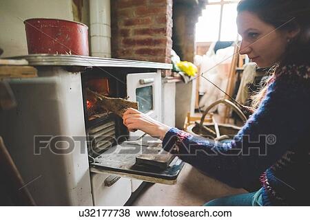 Side view of young woman putting firewood into wood burner View Large Photo Image Stock Photo - Side view of young woman putting firewood into wood burner. Fotosearch