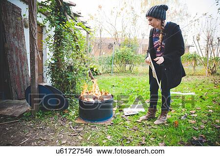 Side view of young woman wearing knit hat by fire in metal barrel View Large Photo Image Stock Photograph - Side view of young woman wearing knit hat by fire in metal barrel. Fotosearch