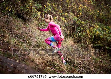 Stock Photography - Side view of young woman wearing sport wear running up hill. Fotosearch